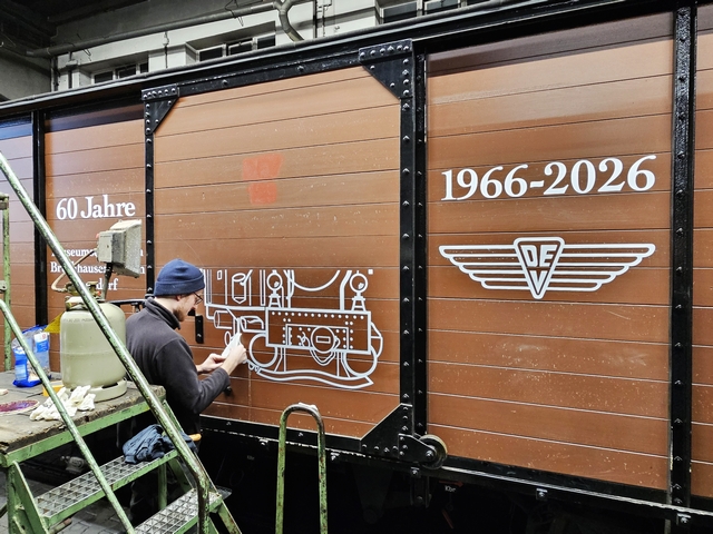 Abb.: Sieht doch schon gut aus! Langsam wird Lok HOYA auf dem Wagen sichtbar. DEV Werbetechnikermeister Peter Ptak, der die Klebefolien vorbereitete, war über die Ausführung der Beklebung begeistert: "Toller Job der Beiden und das bei den Temperaturen!" (Klicken vergrößert).